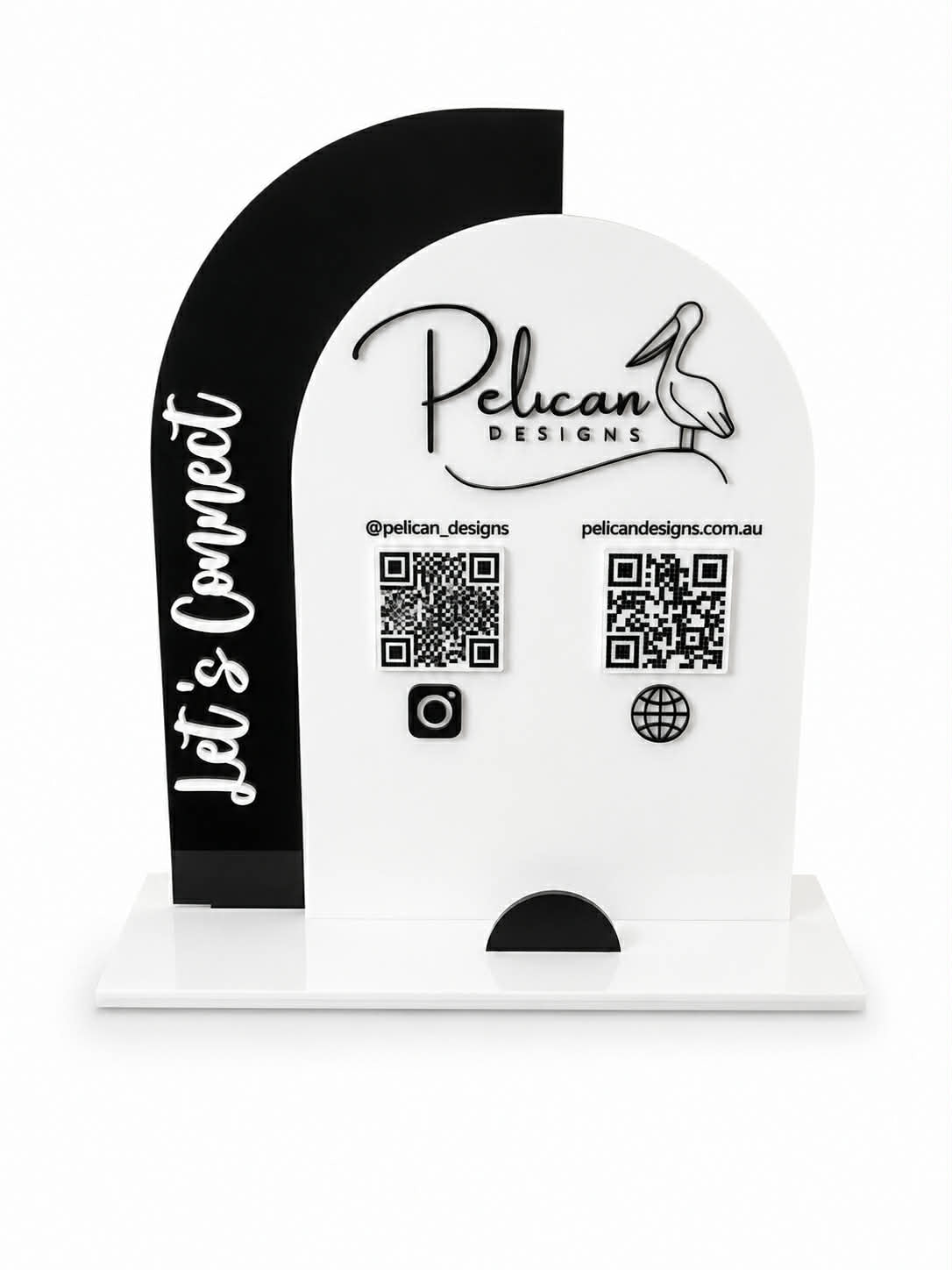 A custom acrylic tabletop sign for Pelican Designs, featuring a white arched main panel with the brand name, social handle, website, and QR codes, alongside a black side panel with the text 'Let's Connect'.