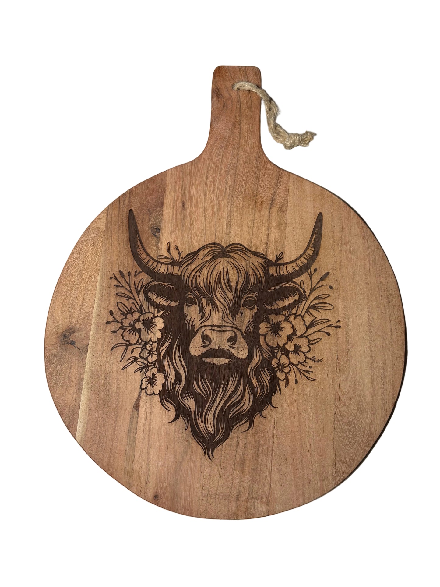 A round wooden serving board with a handle, featuring a dark engraved illustration of a highland cow head surrounded by flowers, with a small rope loop at the handle.