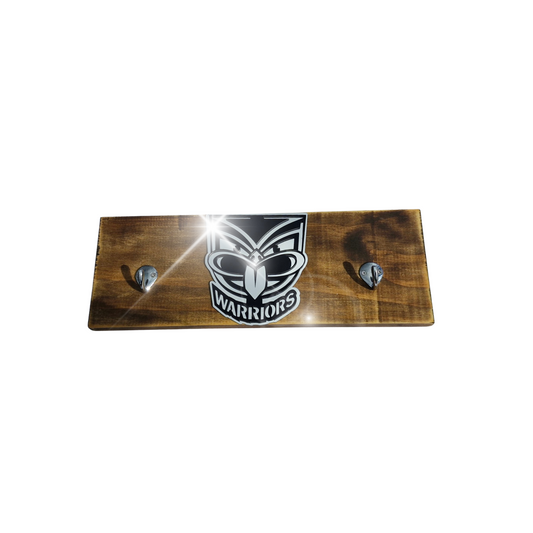 Wooden plaque with 'Warriors' logo and two hooks on a white background