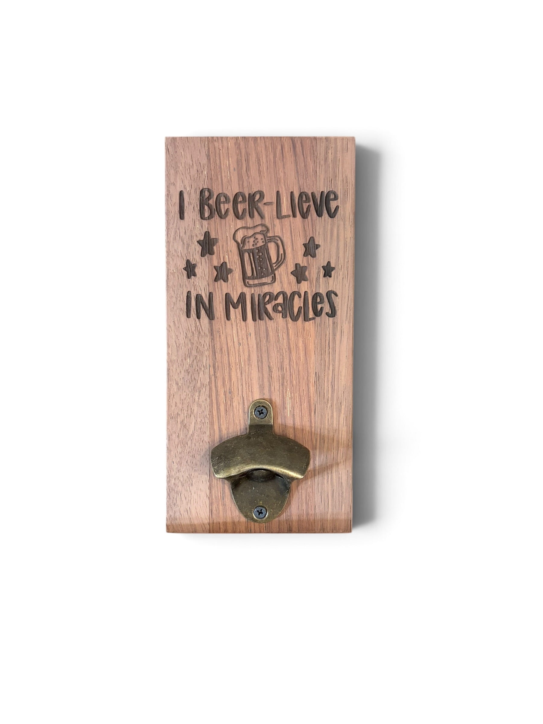A rectangular wooden wall-mounted bottle opener with the engraved text 'I Beer-Lieve IN Miracles' and a beer mug graphic, shown on a plain white background.