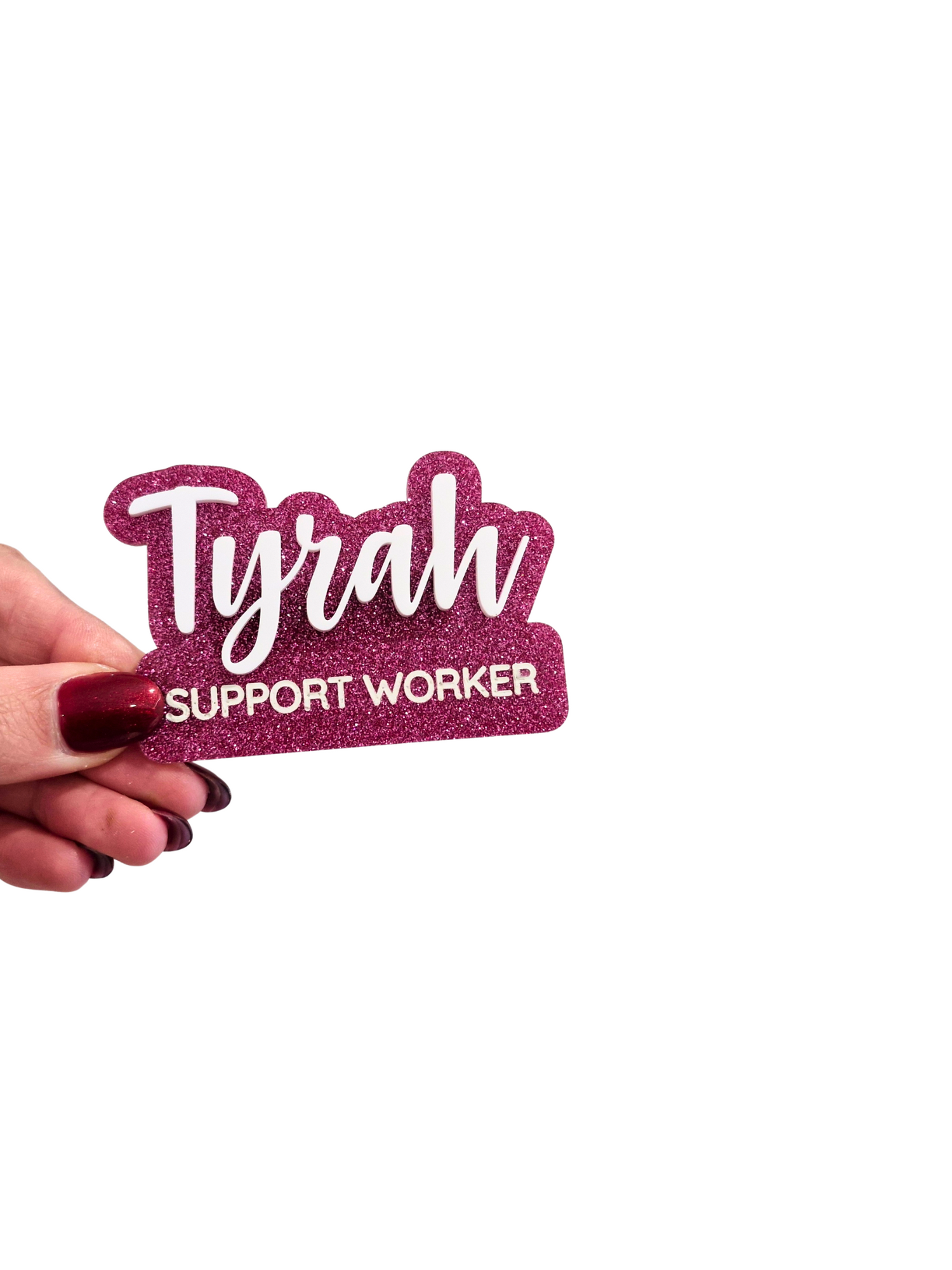 A 3D acrylic name badge with the name 'Tyrah' and the occupation 'Support Worker' printed on it, held by a hand against a white background.