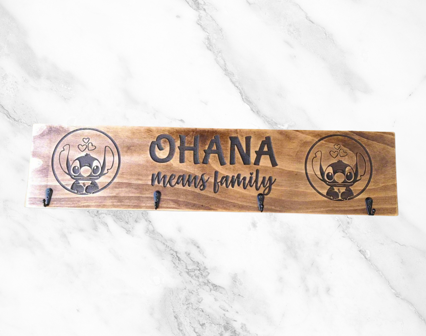 A wooden keyholder plaque with the inscription 'Ohana Means Family' and a small illustration of a family unit.