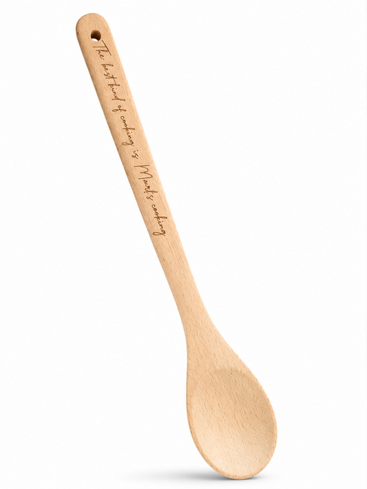 A wooden spoon with engraved text is shown on a clean white background. The engraving reads, 'The best kind of cooking is Marl's cooking.'