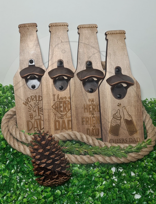 A collection of beer-shaped wooden bottle openers with various humorous engravings, displayed on a table with a rope and pine cones decoration.